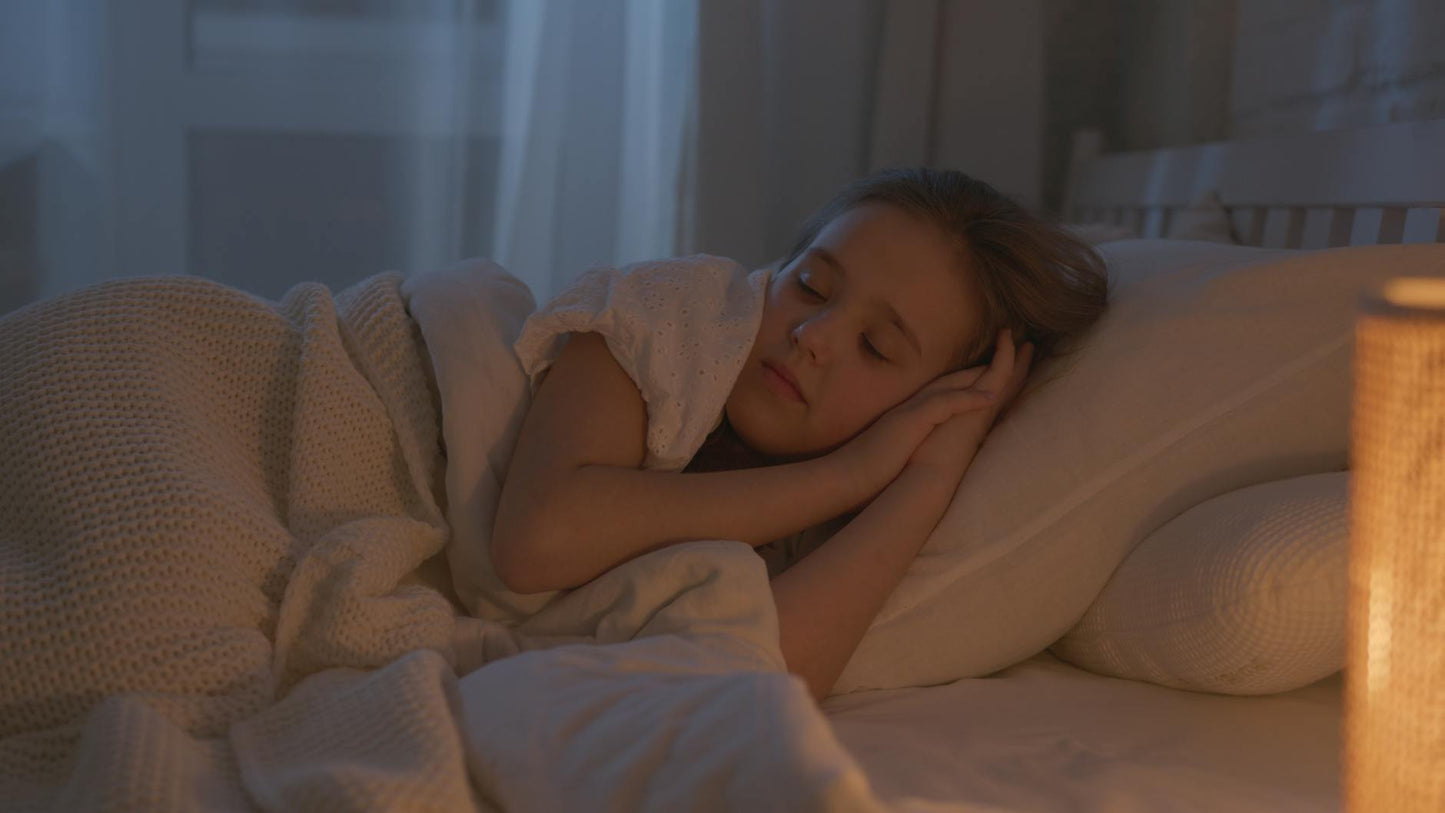 Person sleeping peacefully in a calm bedroom with soft lighting, representing natural sleep support with CBD gummies